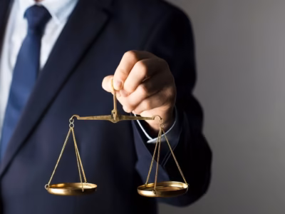 Lawyer in a suit holding golden scales to represent comprehensive legal assistance for associations.