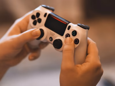 Hands holding a video game controller, illustrating the use of gaming platforms for money laundering.