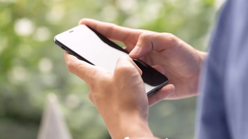 Primer plano de manos usando un smartphone para ilustrar la vulneración del secreto de las comunicaciones.