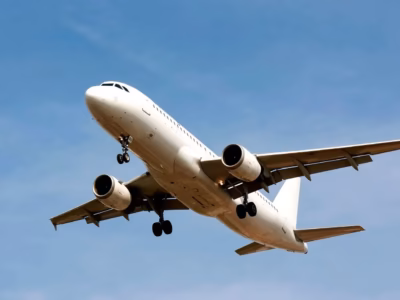 Commercial airplane flying under a clear blue sky, representing the international assignment of workers.