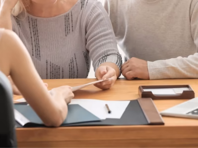 Couple handing a document to their lawyer, illustrating a mutual agreement regarding the marital home.