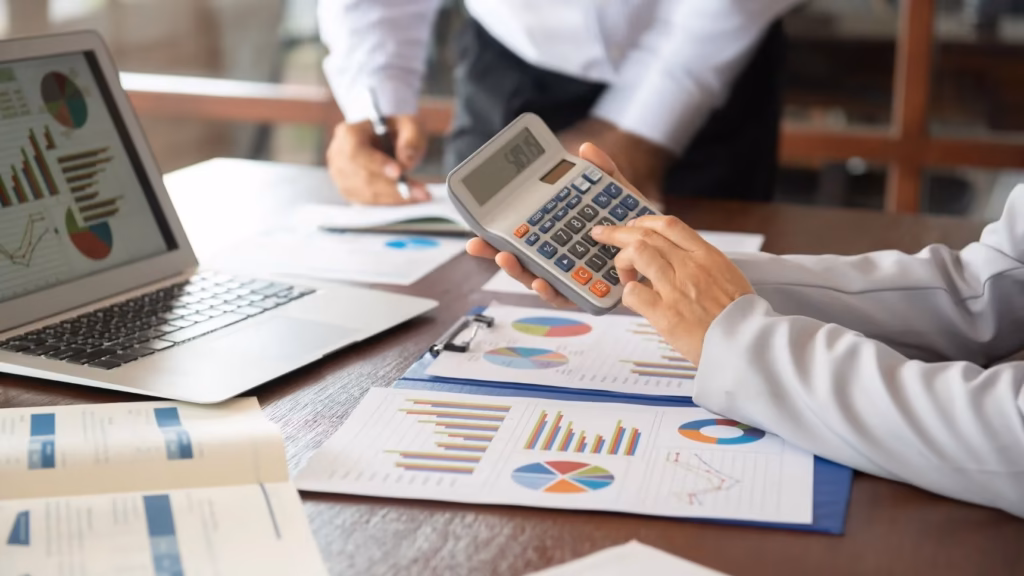 Persona usando calculadora sobre gráficos financieros para calcular el coste de un swap de tipo de interés.