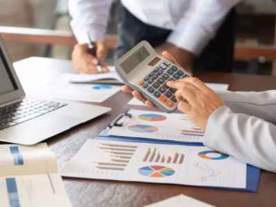 Persona usando calculadora sobre gráficos financieros para calcular el coste de un swap de tipo de interés.
