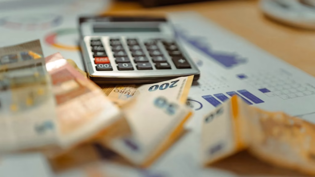 Billetes de euro junto a una calculadora y gráficos, representando el dinero perdido por phishing bancario.