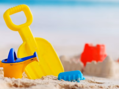 Juguetes de playa en la arena para ilustrar la distribución de vacaciones y visitas de hijos menores.