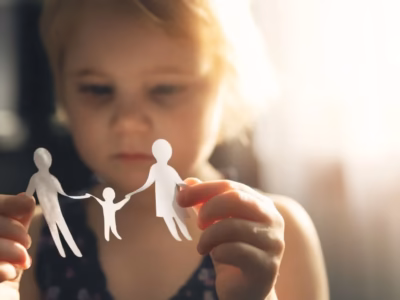 Hands holding a divided paper family, illustrating conflicts over child visitation arrangements and travel expenses.