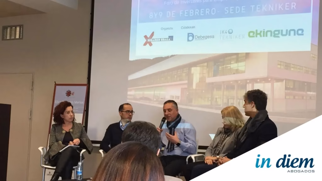 Reunión de profesionales y emprendedores en un foro de inversión con ordenadores y documentos sobre la mesa.