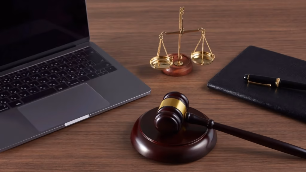 Mazo de juez, balanza de la justicia y portátil en mesa de despacho para abogados de incapacidad permanente.