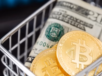 Monedas de Bitcoin y billetes de dólar en un carrito de compra para representar el pago con criptomonedas.