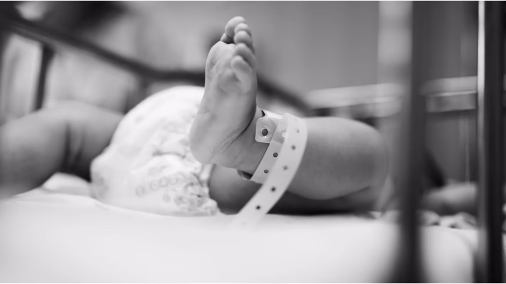 Primer plano del pie de un bebé recién nacido con pulsera de identificación en un hospital.