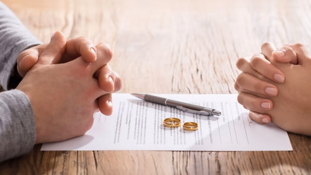 Pareja frente a documentos con alianzas para ilustrar los acuerdos prematrimoniales como medida de protección y estabilidad futura.