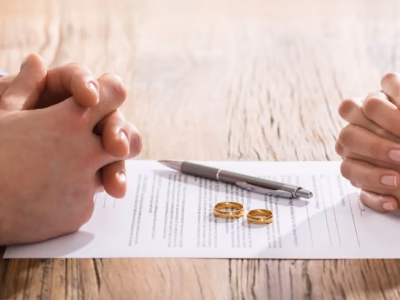 Pareja frente a documentos con alianzas para ilustrar los acuerdos prematrimoniales como medida de protección y estabilidad futura.