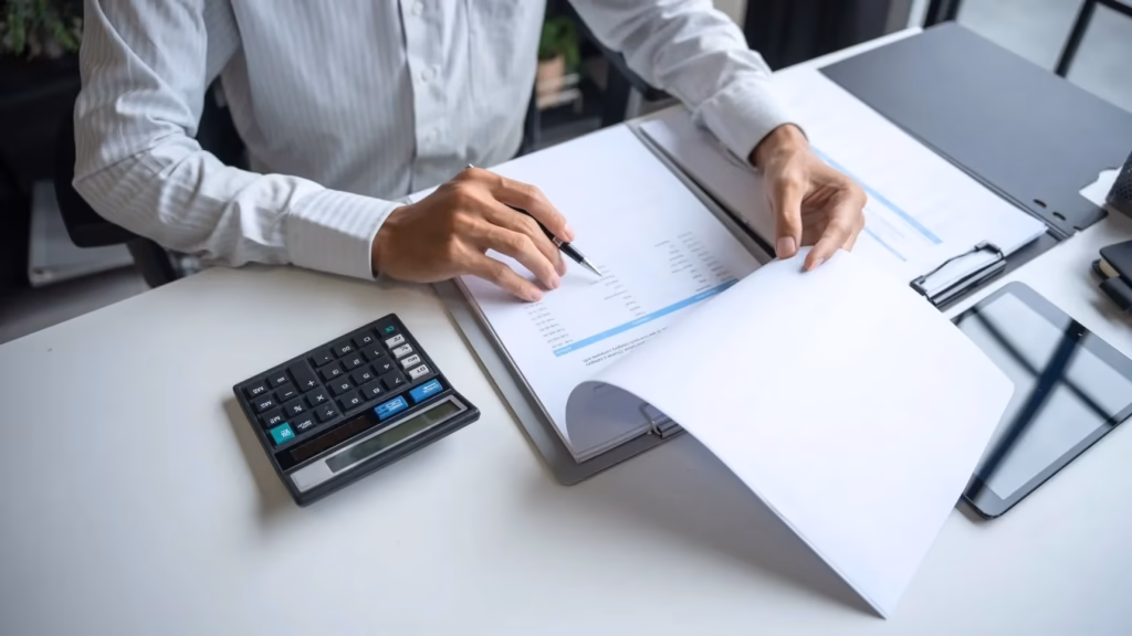 Persona revisando documentos financieros con calculadora. Guía sobre bonificaciones de la cuota de autónomos.