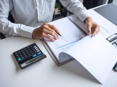Individual reviewing financial documents with a calculator. Guide on self-employed contribution bonuses.