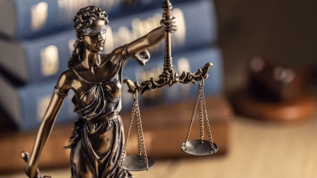 Balanza de la justicia de oro sobre mesa de madera. Compromiso corporativo y corporate compliance.