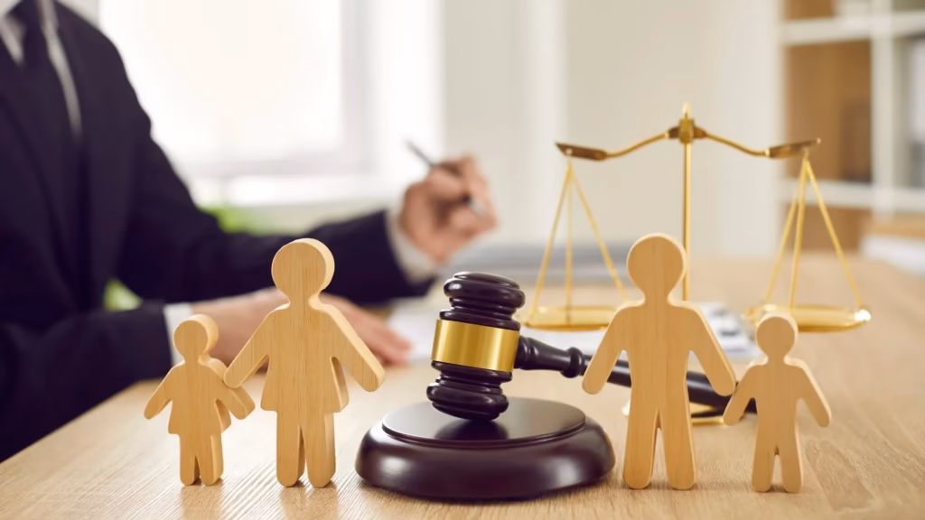 Familia de madera junto a mazo y abogado al fondo para representar la modificacion de medidas en derecho de familia.