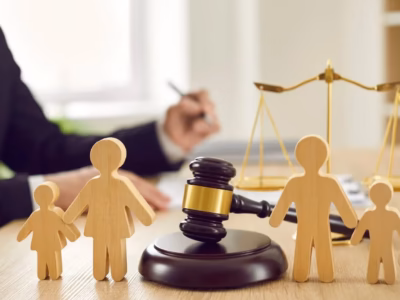 Familia de madera junto a mazo y abogado al fondo para representar la modificacion de medidas en derecho de familia.