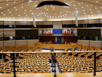Hemiciclo del Parlamento Europeo con banderas de la UE, representando la normativa DAC8 para criptomonedas.