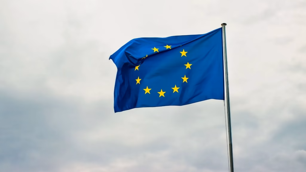 Bandera Unión Europea ondenado al viento en el cielo para ilustrar términos clave del glosario MiCA.