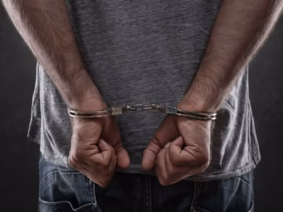 Primer plano de manos de un preso sujetando los barrotes de una celda en prisión preventiva.
