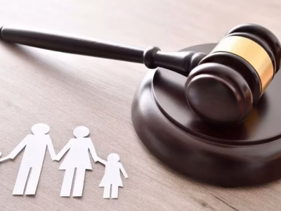 Judge's gavel next to paper figures of a family on a wooden background. Mediation and Family Law.