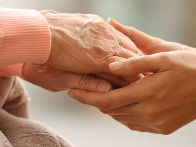 Young person holding the hands of an elderly person as a symbol of estate planning and legacy.