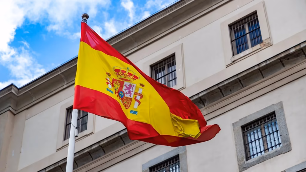 Bandera de España ante edificio oficial para ilustrar consejos legales al comprar una sociedad mercantil española.