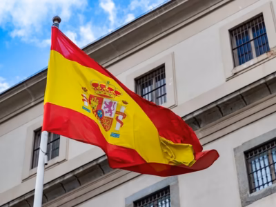 Bandera de España ante edificio oficial para ilustrar consejos legales al comprar una sociedad mercantil española.