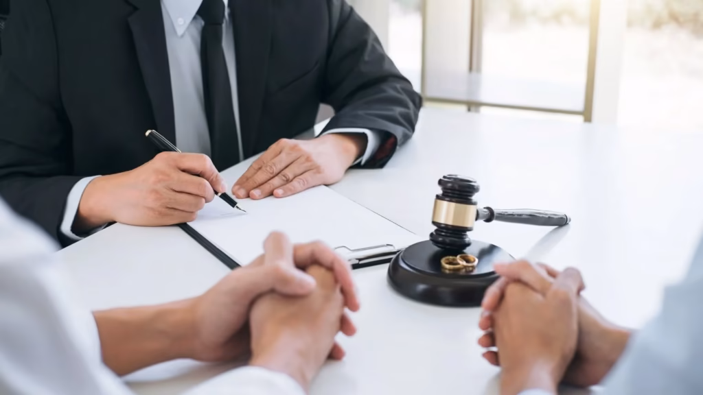 Pareja frente a abogado con mazo de madera para ilustrar un divorcio de mutuo acuerdo sin hijos de forma amistosa.