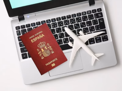 Spanish passport and model airplane on a laptop for processing residency and work visas.