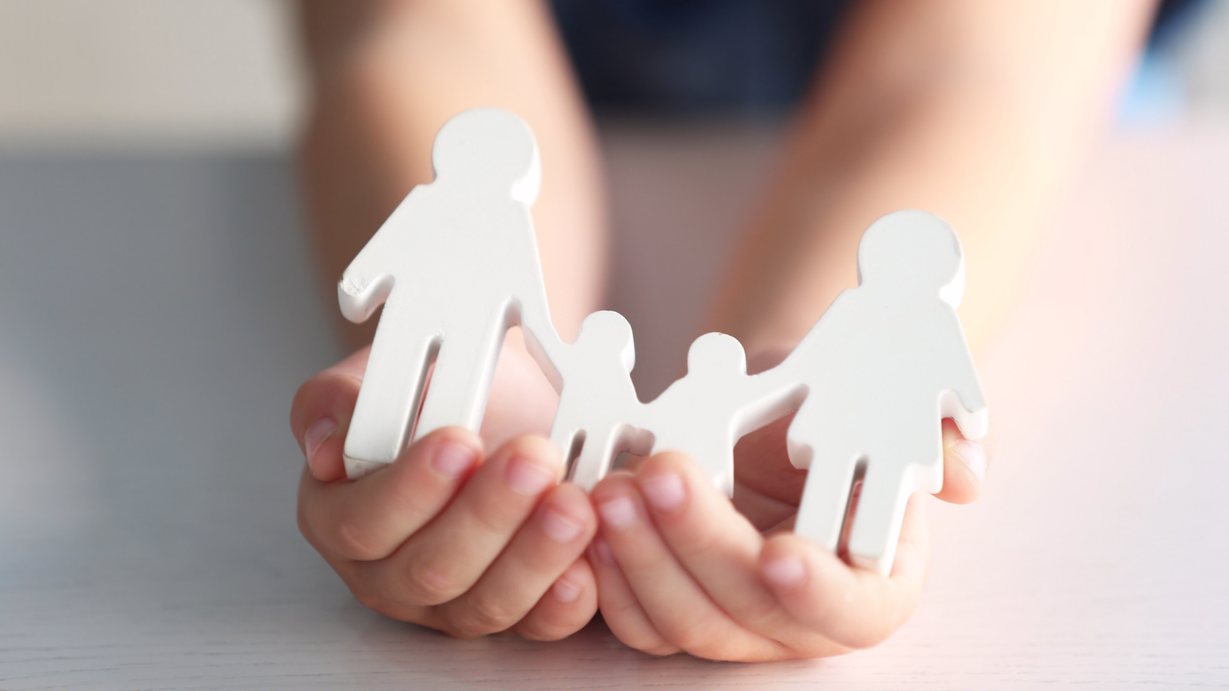 Figuras de una familia sostenidas entre las manos como representación del Derecho de Familia Internacional.