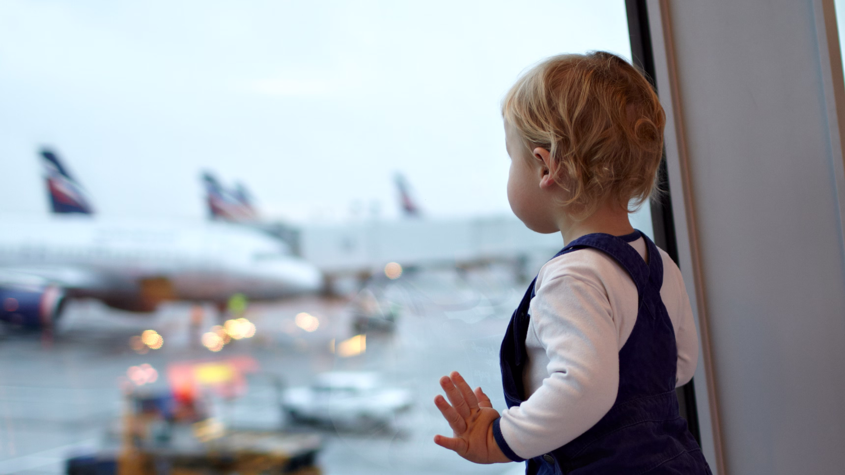 Menor observando aviones desde un aeropuerto como representación del traslado de menores al extranjero.