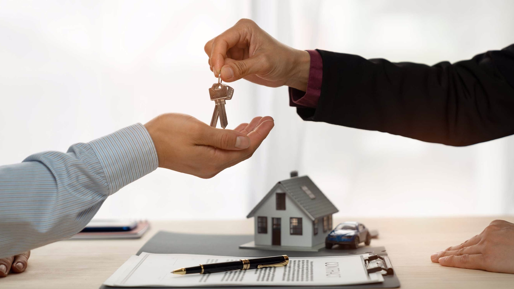 Entrega de llaves en una operación relacionada con una vivienda protegida, con contrato y documentación sobre la mesa.