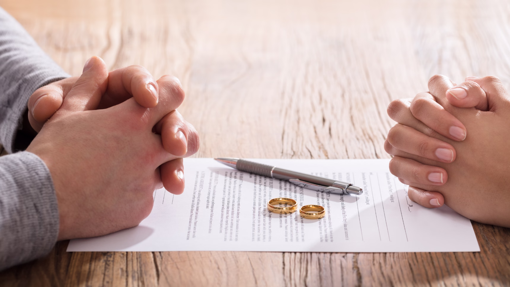 Pareja ante documentación de divorcio y alianzas de boda como representación de un procedimiento de divorcio internacional.