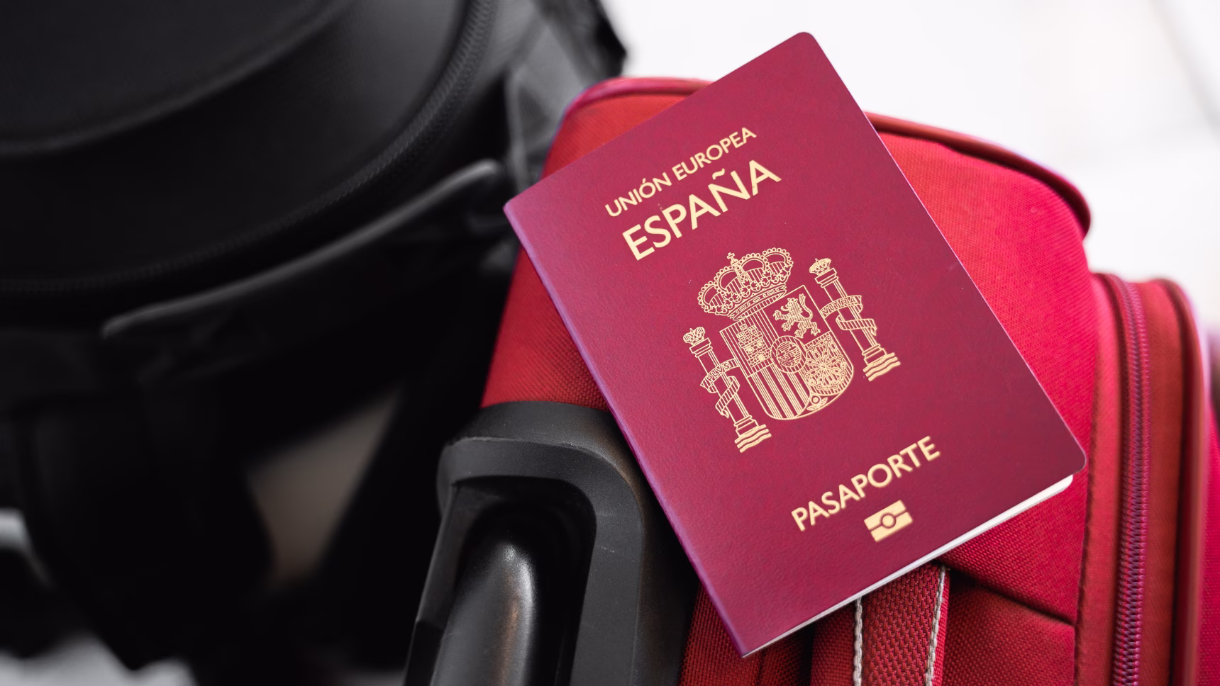 Pasaporte español sobre una maleta de viaje, imagen de la página de arraigo y regularización de extranjeros en España de IN DIEM Abogados