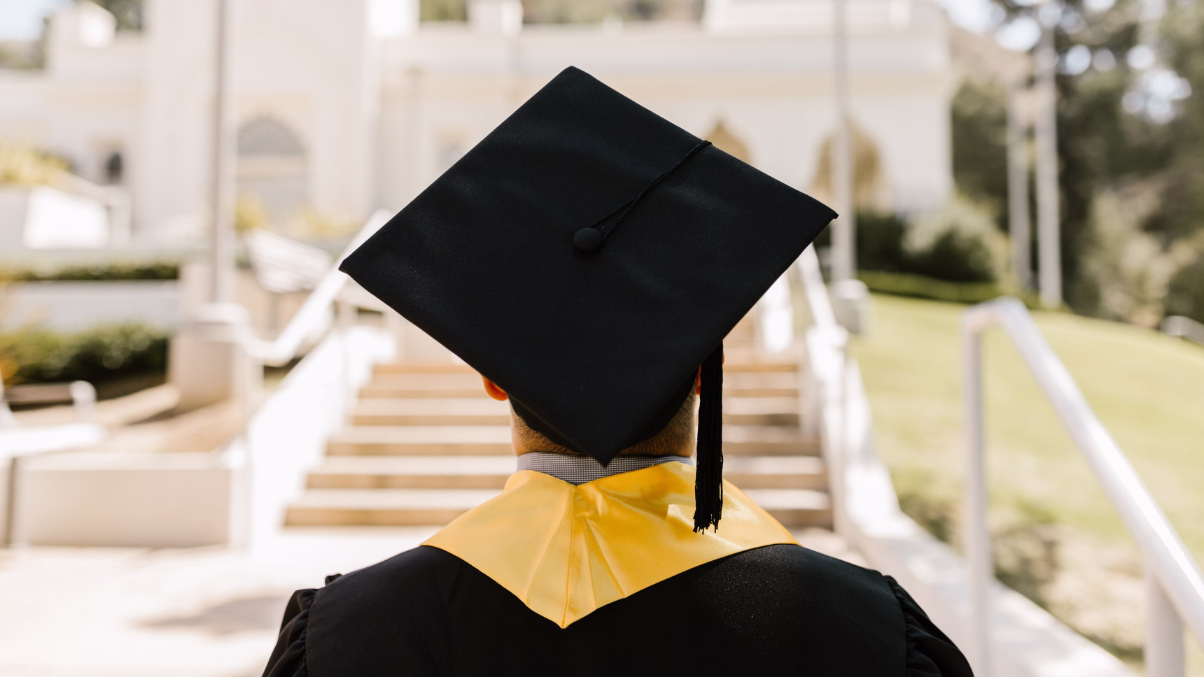 Persona graduada con toga y birrete frente a un edificio universitario, imagen sobre homologación de títulos extranjeros en España
