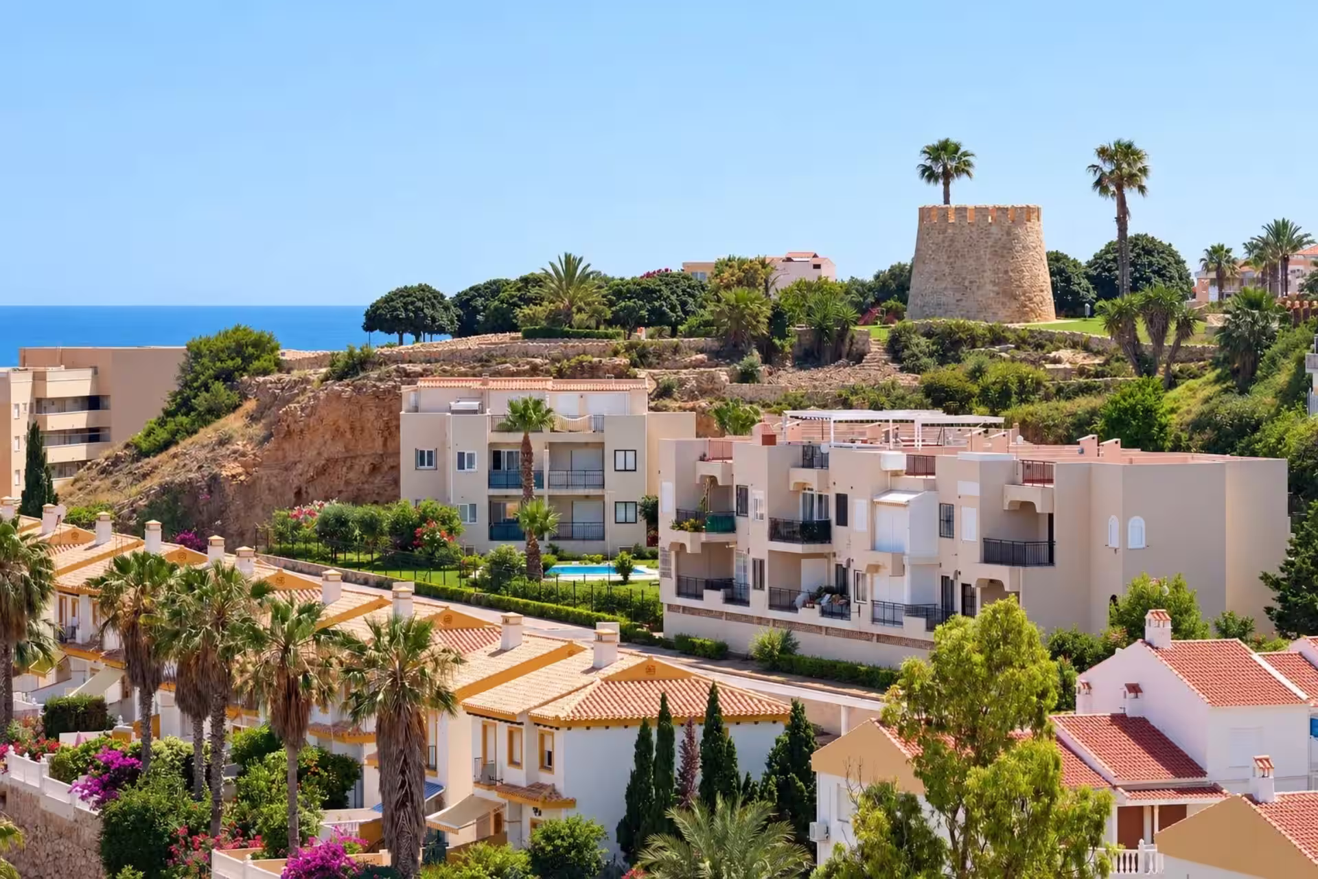 Torre del Moro de Torrevieja sobre una elevación junto a viviendas y vegetación mediterránea.