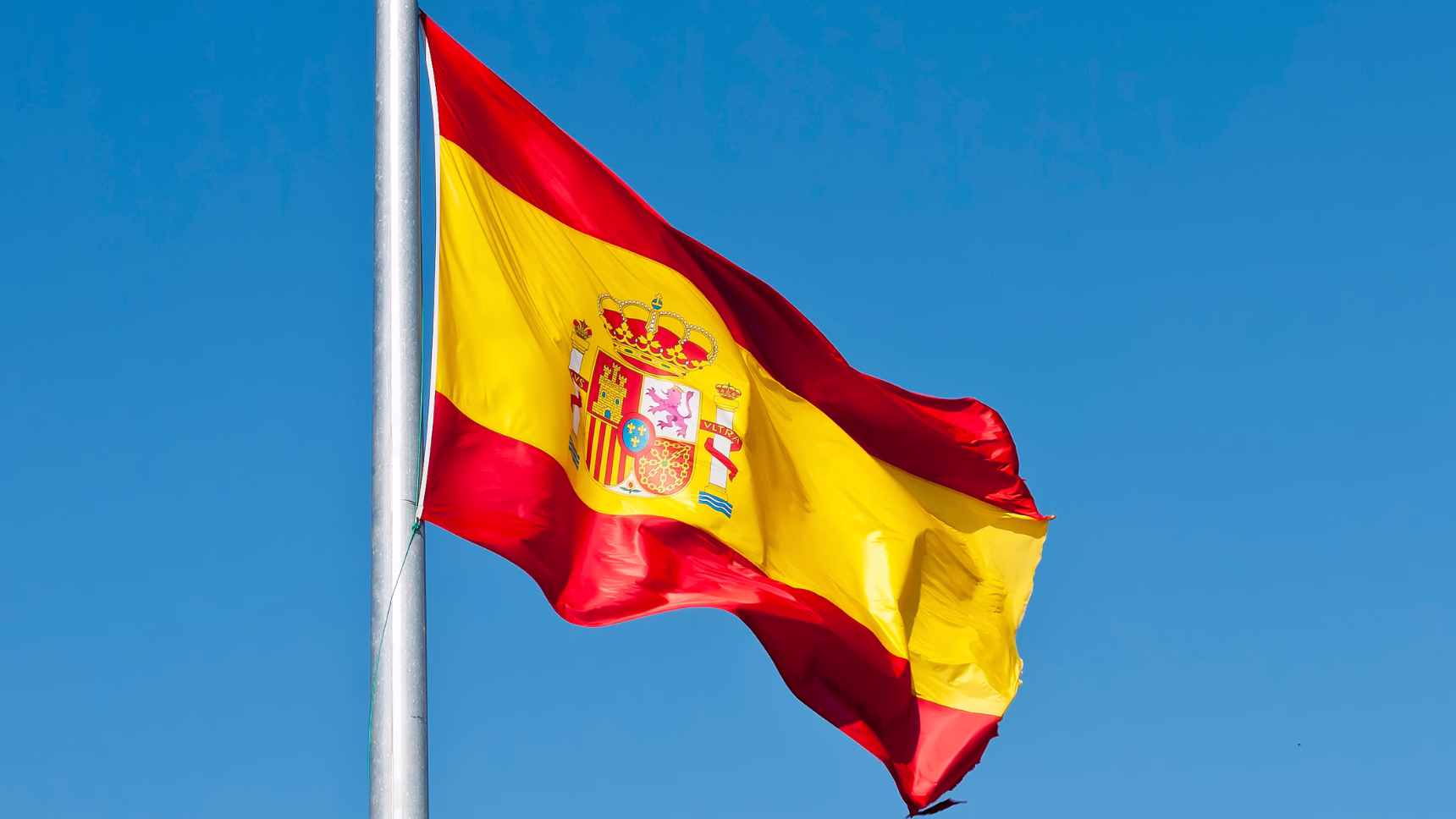 Bandera de España ondeando sobre un cielo azul, imagen representativa de la solicitud de nacionalidad española