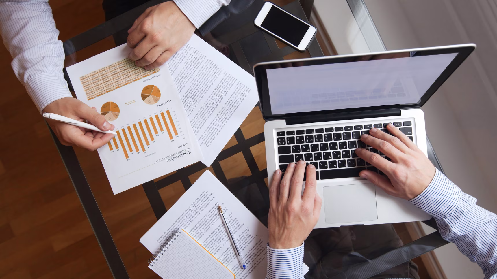 Profesionales trabajando con un ordenador portátil y analizando gráficos empresariales, imagen sobre residencia para nómadas digitales y emprendedores en España