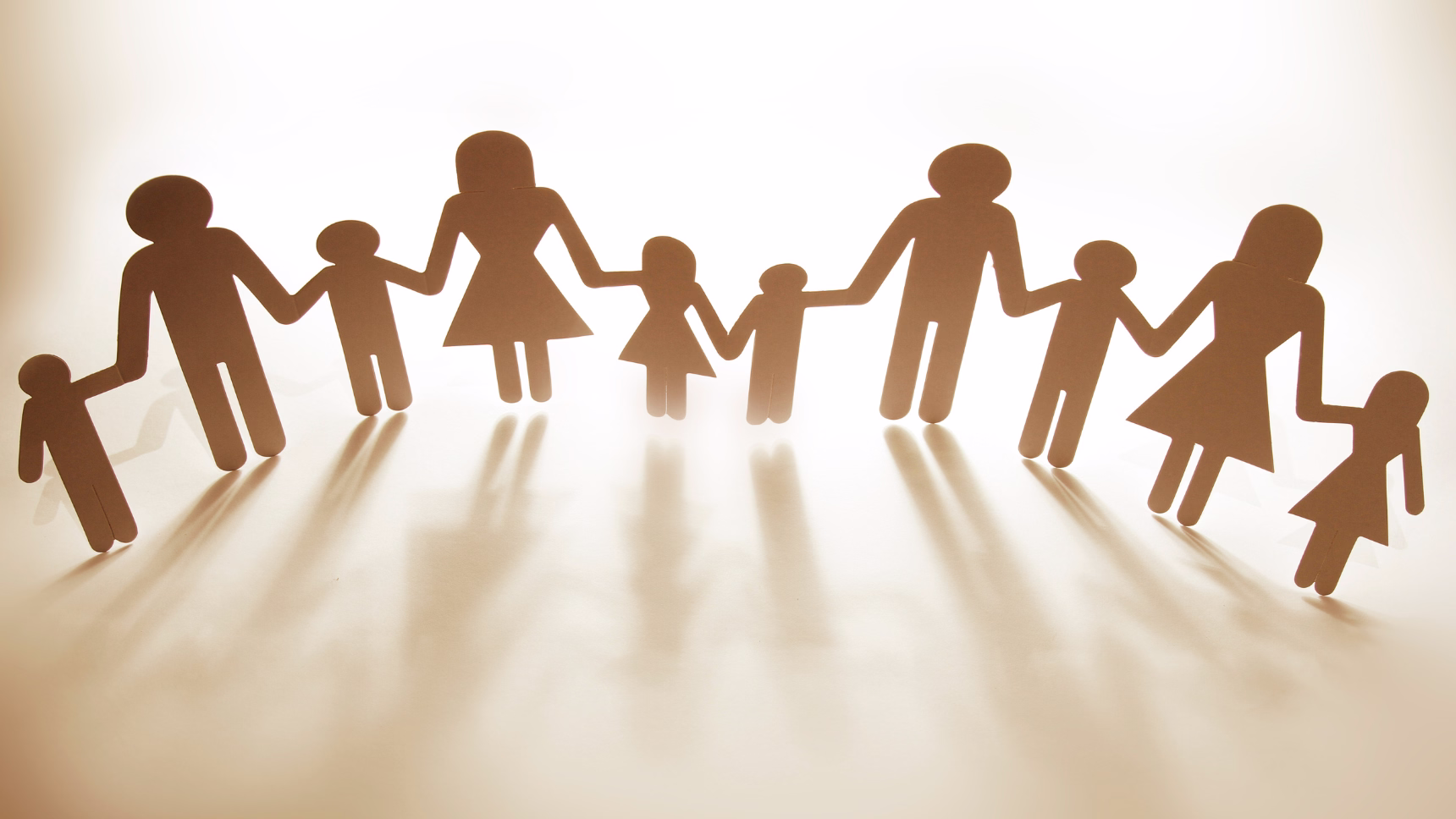 Siluetas de papel de familias con adultos y niños unidos de las manos, símbolo de la reagrupación familiar en España