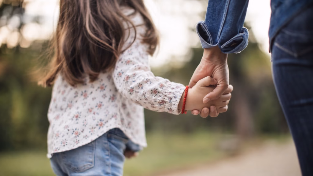 Niña caminando de la mano de una persona adulta, imagen que ilustra la protección del interés superior del menor en un procedimiento de modificación de custodia.