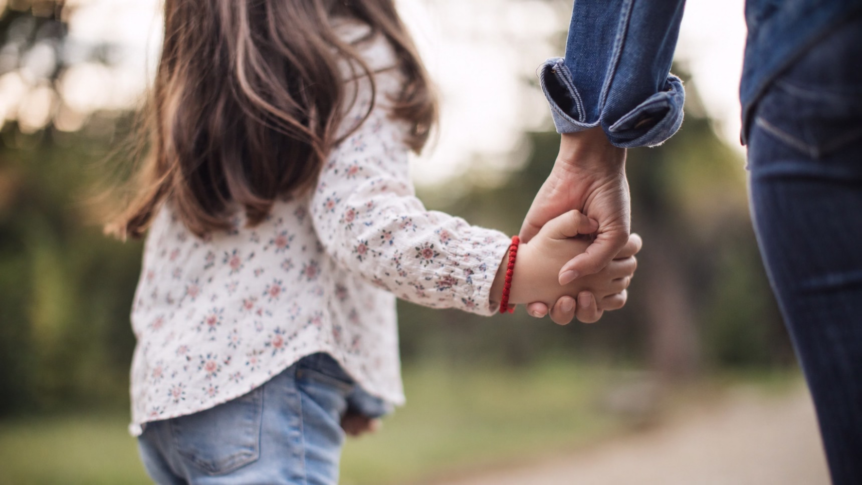 Niña caminando de la mano de una persona adulta, imagen que ilustra la protección del interés superior del menor en un procedimiento de modificación de custodia.