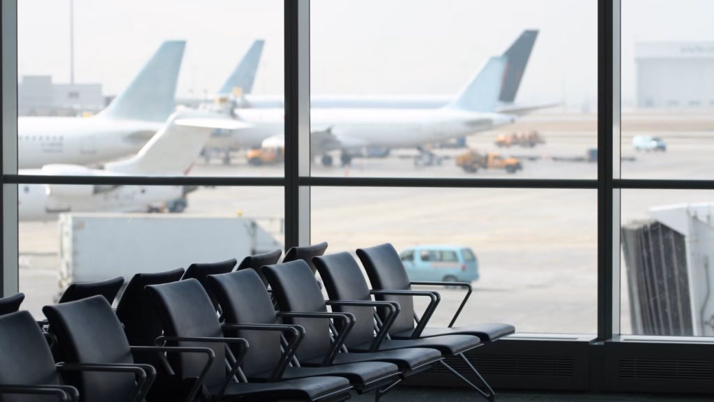 Sala de espera de aeropuerto con aviones al fondo, imagen sobre la entrada en España con antecedentes penales o expulsión previa.