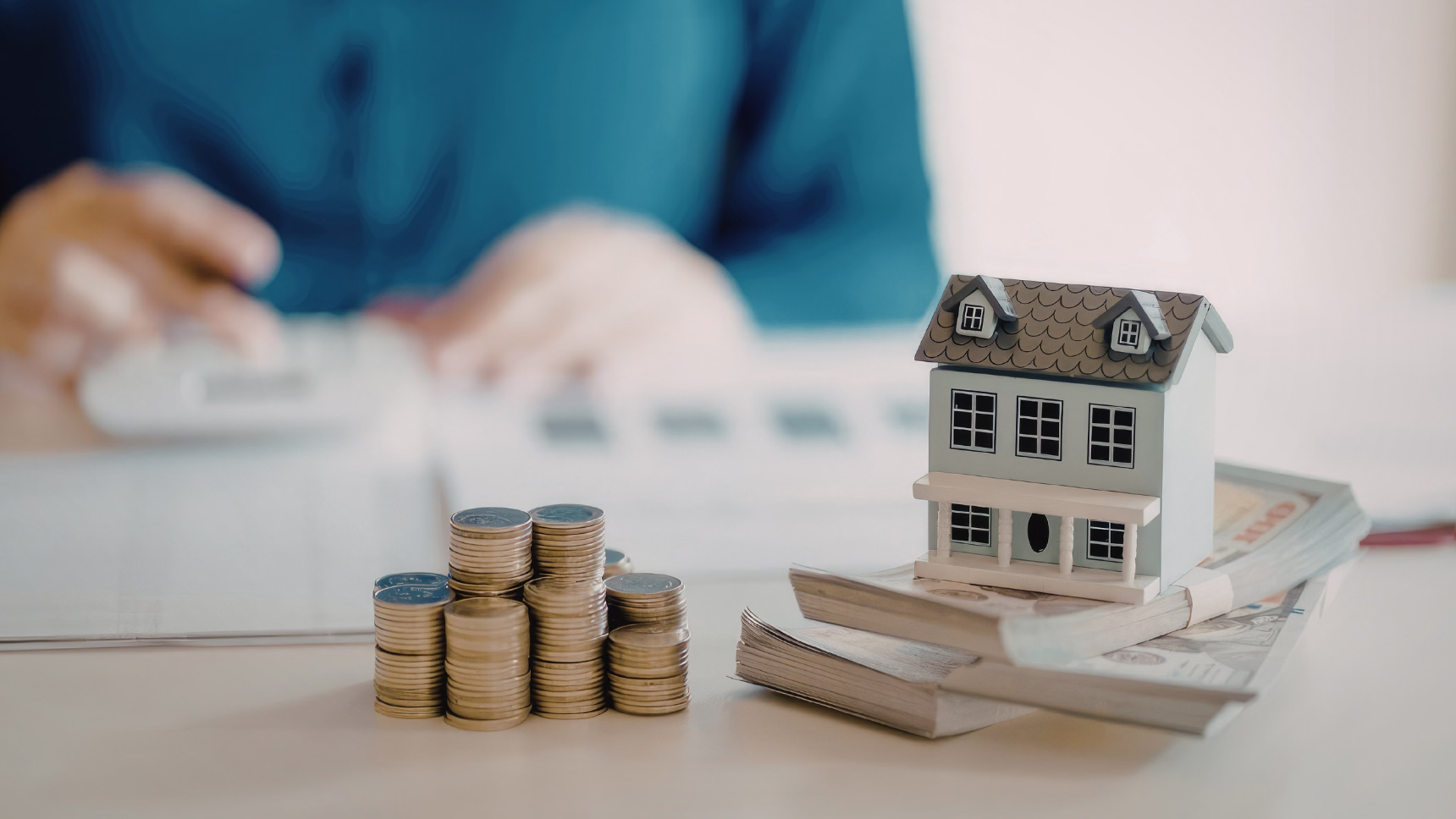 Venta de una VPO: maqueta de vivienda sobre billetes y monedas que representan el precio máximo legal de una vivienda protegida.